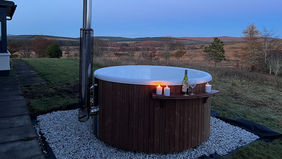 Challenger Lodge wood-fired hot tub at dusk with wine glasses