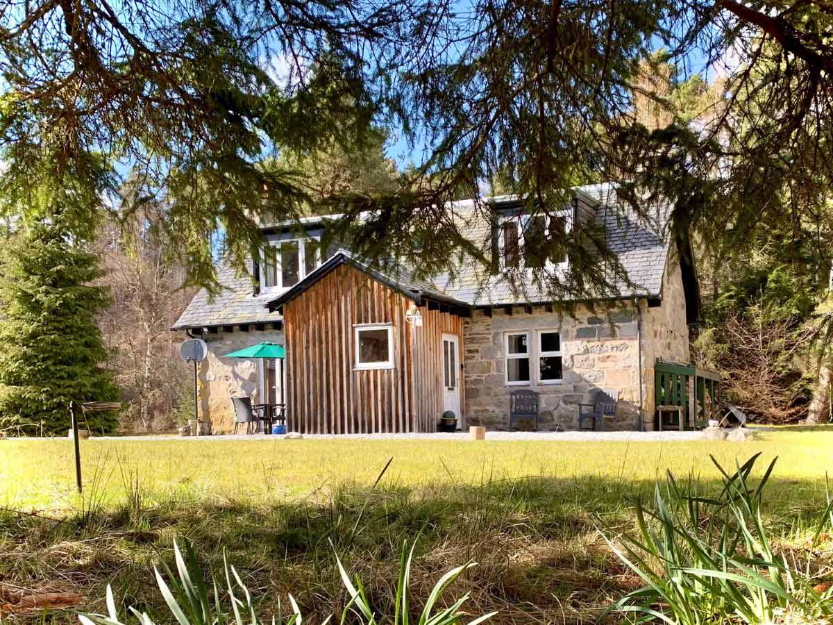 stone and wood cottage in trees Feagour Laggan