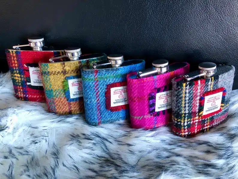 Harris Tweed hip flasks in various colours stood in a row