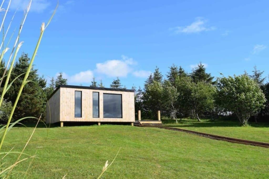 modern wooden cabin with large glass windows with trees in background