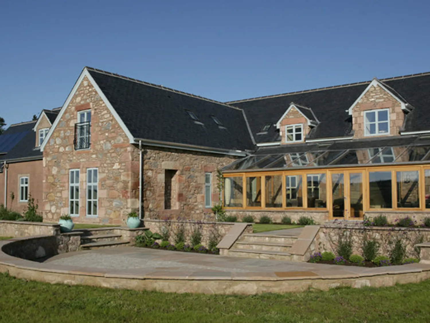 large modern stone built house with lots of glass windows